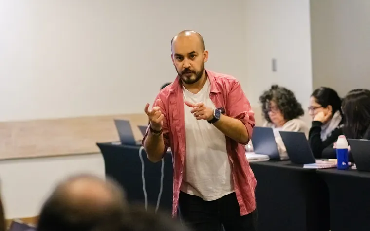 Rodrigo Rojo guiando un taller de IA con un equipo trabajando en sus notebooks