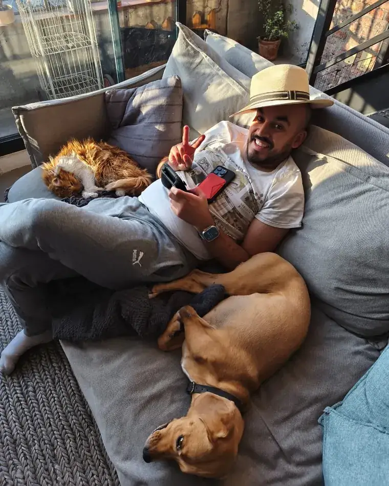 Rodrigo Rojo en el sillón de su casa, con su perro Luffy y su gato Miel Mufasa
